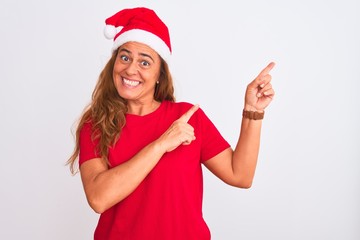 Middle age mature woman wearing christmas hat over isolated background smiling and looking at the...