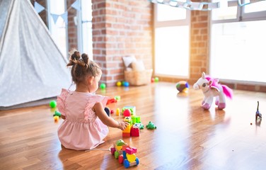 Young beautiful toddler sitting on the floor playing with small cars toys at kindergaten