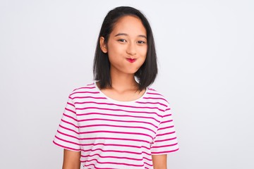 Fototapeta premium Young chinese woman wearing striped t-shirt standing over isolated white background puffing cheeks with funny face. Mouth inflated with air, crazy expression.