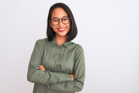 Young chinese woman wearing green shirt and glasses over isolated white background happy face smiling with crossed arms looking at the camera. Positive person.