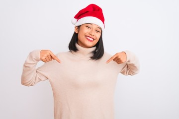 Young beautiful chinese woman wearing Christmas Santa hat over isolated white background looking confident with smile on face, pointing oneself with fingers proud and happy.