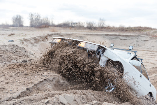 Rally on the sand. Broken car rides on the sand. Off-road driving. The car jumps on a springboard.
