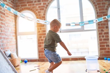 Young caucasian kid playing at kindergarten with toys. Preschooler boy happy at playroom.