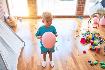 Young caucasian kid playing at kindergarten with toys. Preschooler boy happy at playroom.