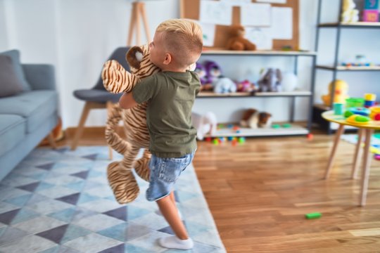 Young caucasian kid playing at kindergarten with toys. Preschooler boy happy at playroom.
