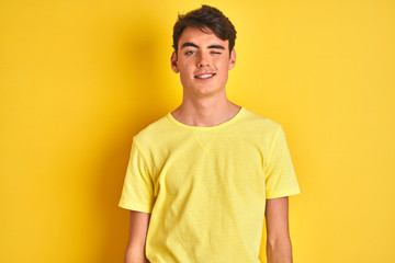 Fototapeta premium Teenager boy wearing yellow t-shirt over isolated background winking looking at the camera with sexy expression, cheerful and happy face.