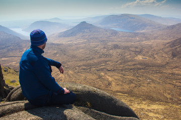 Tourist and hiker in blue jacket looking at stunning and breathtaking view from top of the hill....