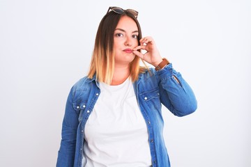 Beautiful woman wearing denim shirt standing over isolated white background mouth and lips shut as...