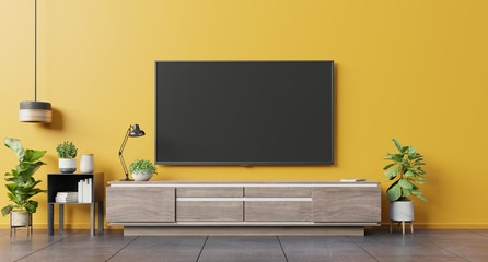 TV on cabinet in modern living room on yellow wall background.