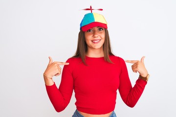 Young beautiful girl wearing fanny cap with propeller standing over isolated white background...