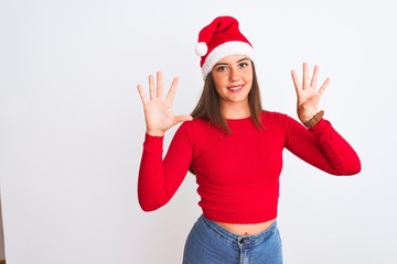 Young beautiful girl wearing Christmas Santa hat standing over isolated white background showing and pointing up with fingers number nine while smiling confident and happy.