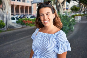Fototapeta premium Young beautiful woman smiling happy walking on city streets on a sunny day of summer
