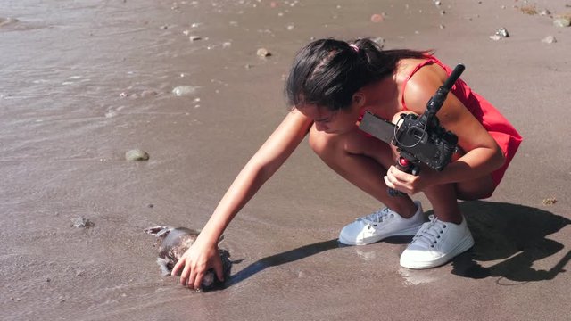 A female vlogger found a dead fish at the seashore when filming video.