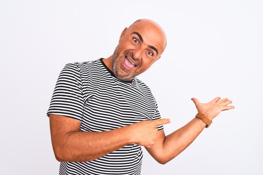 Middle age handsome man wearing striped navy t-shirt over isolated white background Showing palm hand and doing ok gesture with thumbs up, smiling happy and cheerful