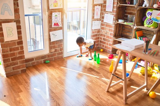 Beautiful african american toddler playing with cars and skittles at kindergarten