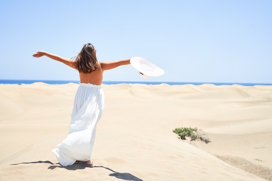 Young beautiful woman sunbathing with open arms enjoying summer vacation at maspalomas dunes beach