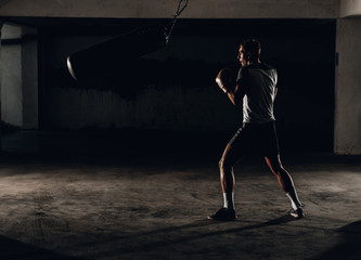 Kickboxer training in the garage kicking the punch bag