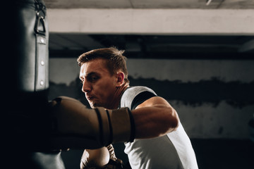 Plakat Young Caucasian boxer training alone with punching bag in health club