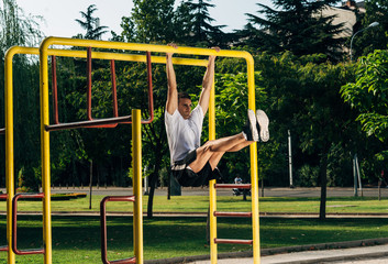 Young man makes a pull-up on the crossbar in the outdoor gym in the park