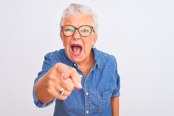 Senior grey-haired woman wearing denim shirt and glasses over isolated white background pointing...