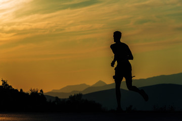 Sporty man jogging over blue sky on mountain path