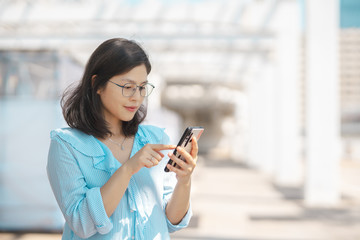 Young woman using smartphone under   harsh sun light