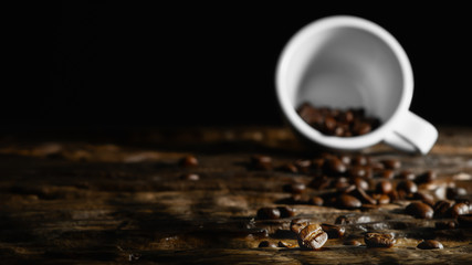 beverage background of roasted coffee beans with laying coffee cup on wooden table