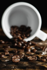 beverage background of roasted coffee beans with laying coffee cup on wooden table