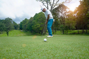 Blurred golfers are playing golf in the evening golf course.