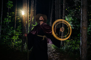 Fototapeta na wymiar Young wizard with a magic staff in dark forest