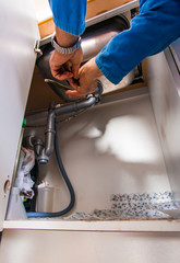 An old age plumber work with pilers on the sink