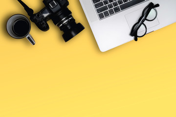 Flat lay, top view of laptop, photography device and cooffe cup on clean yellow color table. image create blank copy space.