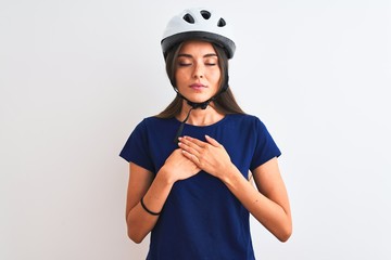 Young beautiful cyclist woman wearing security bike helmet over isolated white background smiling with hands on chest with closed eyes and grateful gesture on face. Health concept.