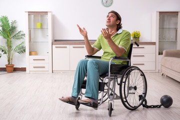 Young male invalid in wheel-chair suffering at home