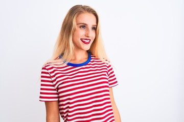 Young beautiful woman wearing red striped t-shirt standing over isolated white background looking away to side with smile on face, natural expression. Laughing confident.