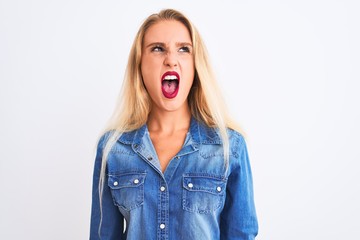 Young beautiful woman wearing casual denim shirt standing over isolated white background angry and mad screaming frustrated and furious, shouting with anger. Rage and aggressive concept.