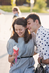 Happy young couple in love having fun and walk on the summer day. Girlfriend and boyfriend spend time together in park. Lovers enjoying themselves prank. Street fast food. Ice-cream and milkshake