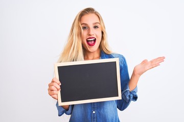 Young beautiful teacher woman holding blackboard standing over isolated white background very happy and excited, winner expression celebrating victory screaming with big smile and raised hands