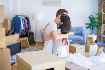 Young beautiful couple hugging at new home around cardboard boxes