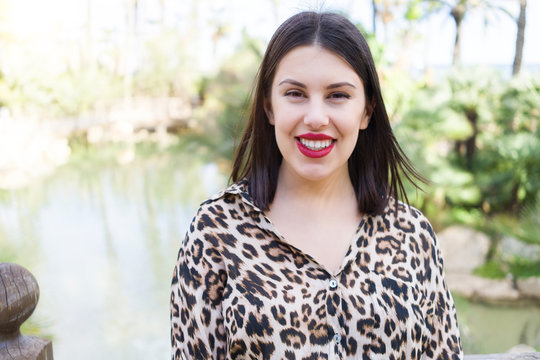 Young beautiful woman with red lips smiling happy at garden