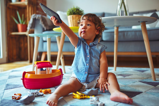 Beautiful toddler child girl sitting on the carpet playing with smartphone