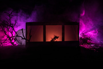 Old house with a Ghost in the forest at night. Horror silhouette at the window. Old building in forest. Surreal lights. Horror Halloween concept