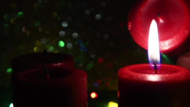 Red candles. Selective focus on first candle. Advent theme video. Hand appearing lighting up the second, third and fourth candle separately. Real time video. Christmas decoration.