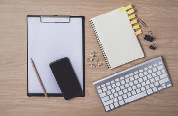 Workspace with diary or notebook and smart phone, clipboard, keyboard, pencil, sticky notes on wooden background