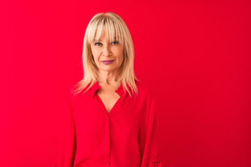 Fototapeta premium Middle age woman wearing elegant shirt standing over isolated red background Relaxed with serious expression on face. Simple and natural looking at the camera.