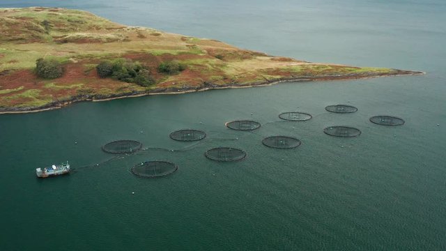 Fish farms in Scotland. Beautiful aerial footage with mountains in the background. Salmon farms. Fish farming.