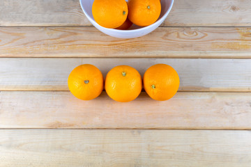 Top view Fresh oranges in white bowl on wood table. With copy space for text or design.