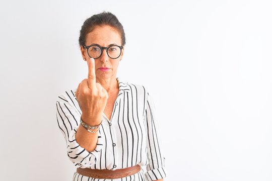Middle age businesswoman wearing striped dress and glasses over isolated white background Showing middle finger, impolite and rude fuck off expression