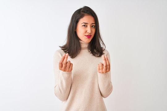 Beautiful chinese woman wearing turtleneck sweater standing over isolated white background doing money gesture with hands, asking for salary payment, millionaire business