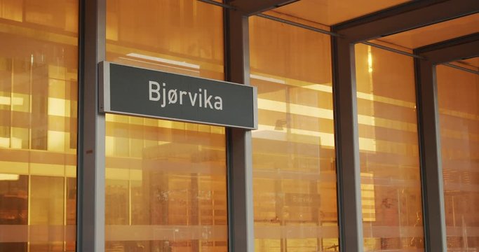 Cinema 4K gimbal near shot with parallax motion of a Bj&oslash;rvika sign on a new orange bus, train and tram station in the new Bj&oslash;rvika Opera quarter project, in Oslo Norway.